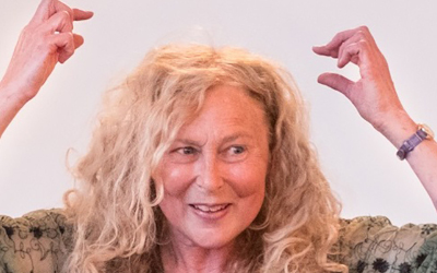 Closeup of creative writer Deb Winter, hands enthusiastically above her head, in deep storytelling mode