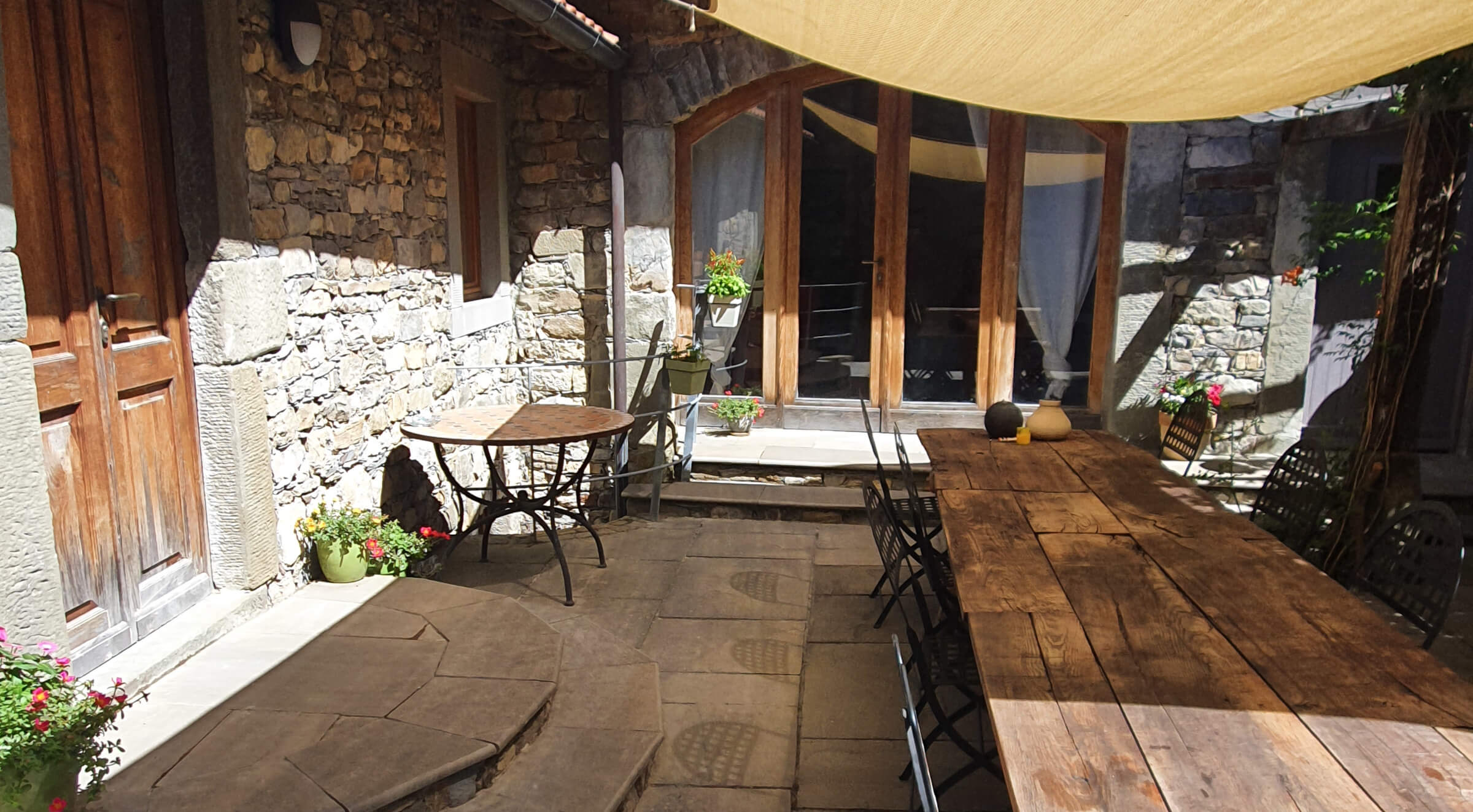 Stone courtyard with large wooden table with seating for eight guests